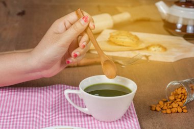 El ahşap üzerine sıcak ve taze yeşil çay bir tahta kaşık hold