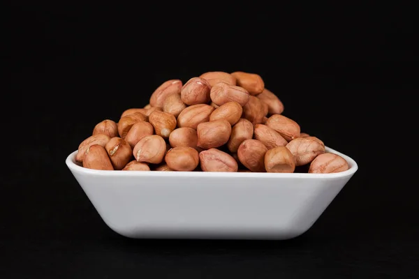 Ground nut in green dish with fork on black background — Stock Photo, Image