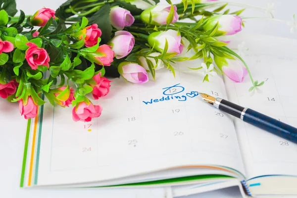 Hochzeitsnotiz auf einem Kalender erinnert mit Blume und Stift an den Hochzeitstag — Stockfoto