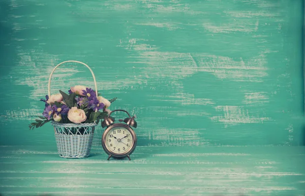 flower in basket with alarm clock on wood background.
