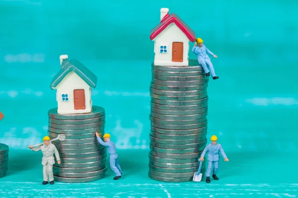 miniature worker and small house on coin stack