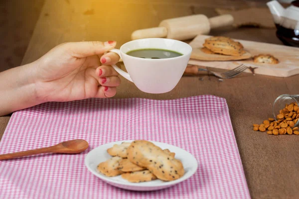 Elini tut sıcak ve taze yeşil çay ile ev ahşap üzerine deli