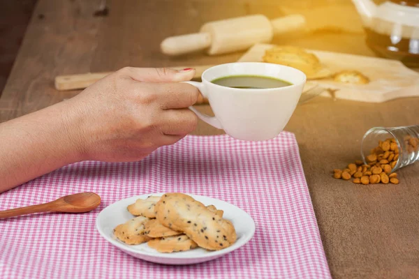 Elini tut sıcak ve taze yeşil çay ile ev ahşap üzerine deli