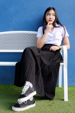 Genç öğrenci kız okulda Tekdüzen bankta oturmak