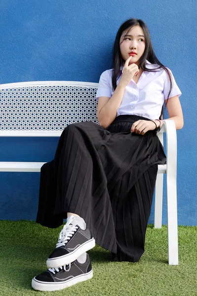 Genç öğrenci kız okulda Tekdüzen bankta oturmak