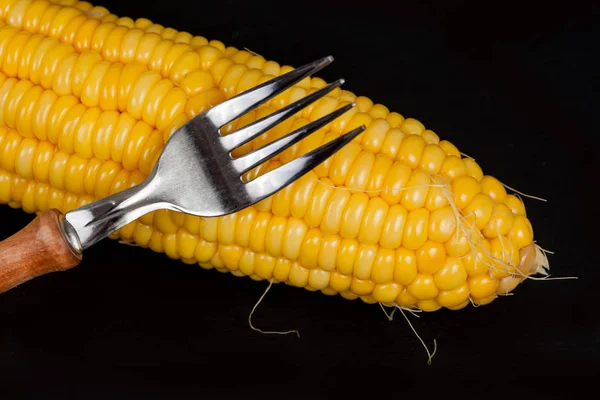 Gele verse maïs met vork op zwarte achtergrond — Stockfoto