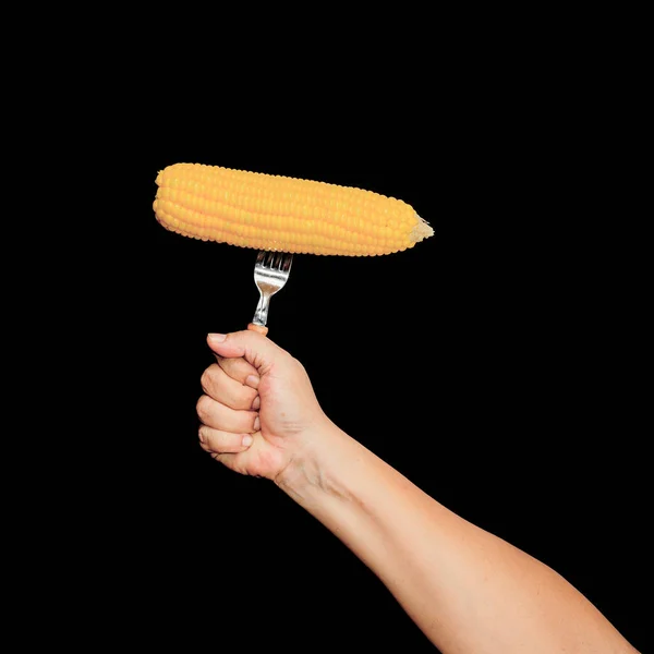 Hand houden gele verse maïs met vork op zwarte achtergrond — Stockfoto