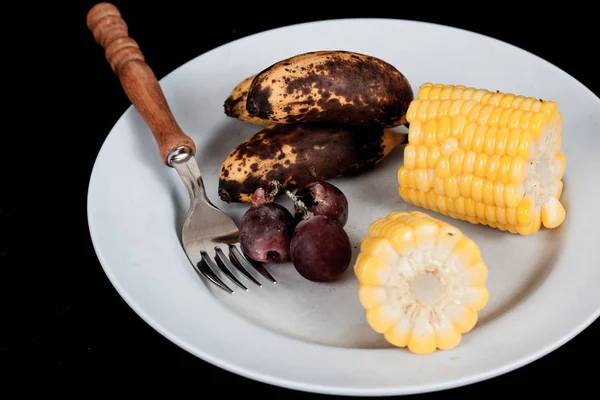 Rifiuti alimentari, mela, banana, mais e uva frutta con forchetta sul piatto — Foto Stock