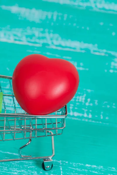 Rood hart ondertekenen in winkelwagen op kleur hout — Stockfoto
