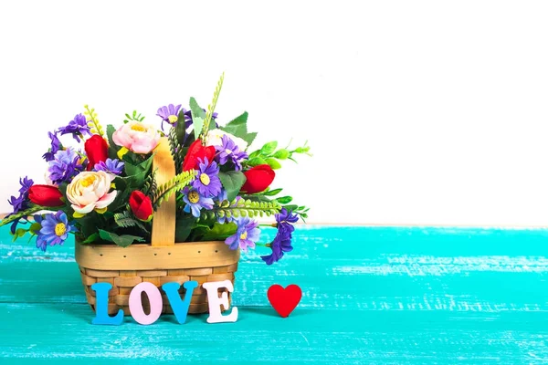 Letras de amor de color en madera con cesta de flores — Foto de Stock
