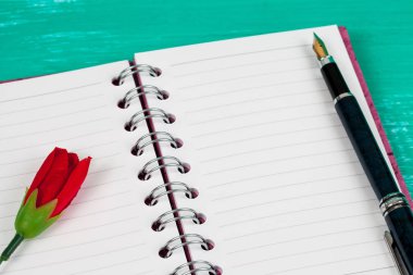 kitap Not ahşap masa arka plan üzerinde kırmızı gül