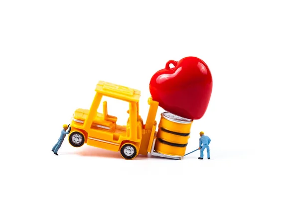Trabalhador em miniatura e pequena empilhadeira com sinal de coração de amor — Fotografia de Stock