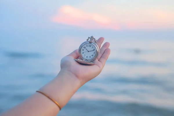 pocket watch in hand on sea scape background.