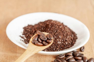 Ahşap masa üzerinde beyaz tabak içinde kahve tozu.