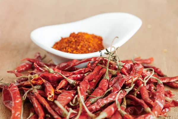 Cayenne pepper in white dish and dried chilli on wood table. — Stock Photo, Image