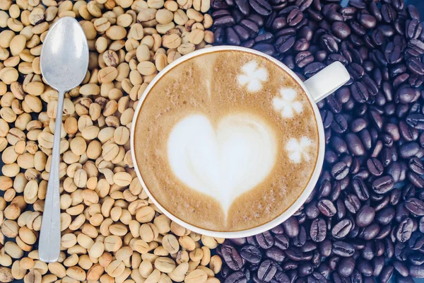 Raw coffee beans with hot latte art on open space. — Stock Photo, Image
