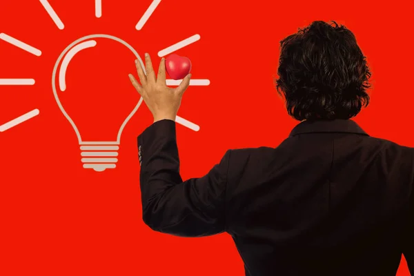 Business man holding red heart ball with light bulb.idea concept.