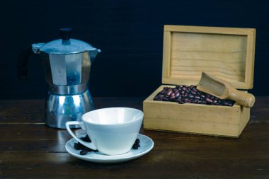 Eski ahşap arka planda beyaz kahve fincanında kahve çekirdeği..