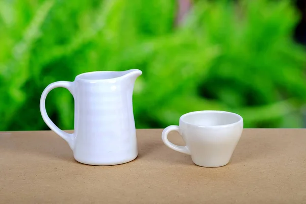 Tasse à café blanche et pot sur table en bois avec fond nature . — Photo