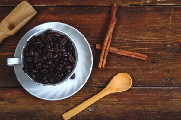 Grain de café en tasse de café blanche sur fond de vieux bois . — Photo