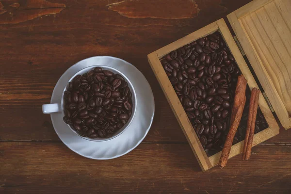 Grain de café en tasse de café blanche sur fond de vieux bois . — Photo