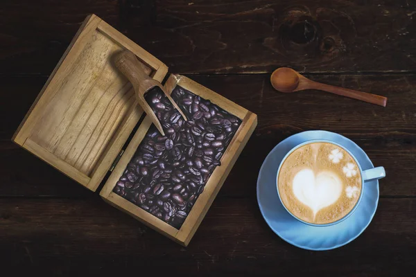 Coffee bean in wood box with late art coffee on old wood backgro — Stock Photo, Image
