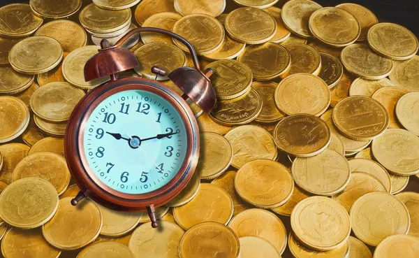 Reloj despertador sobre fondo de dinero moneda de oro. Concepto para el tiempo es —  Fotos de Stock