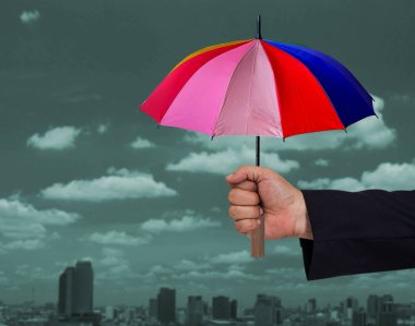 İş adamı elinde renkli bir şemsiye tutuyor. .