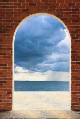 Kırmızı tuğlalı duvardaki kapı deniz manzarasına giden yol..