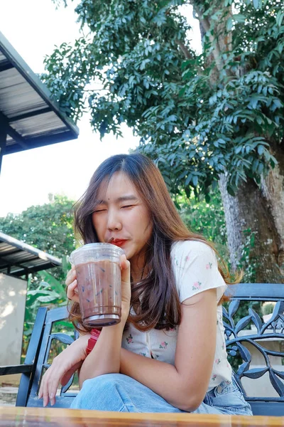 Mujer joven bebiendo café helado en la cafetería en el patio trasero . — Foto de Stock