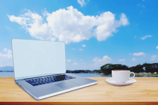 Working outdoor with  laptop and hot coffee on table with blue sky.