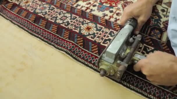 Ein Mann schneidet einen Teppich mit einem speziellen Webstuhl. Schöner Teppich in Vorbereitung. — Stockvideo