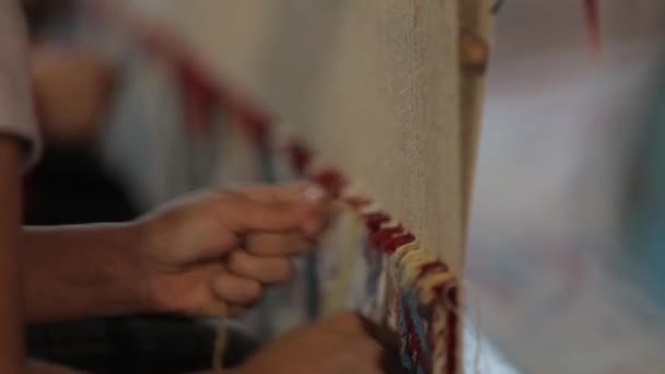 Pocas mujeres cosen una alfombra. El primer plano de las manos trabaja detrás de un telar — Vídeo de stock