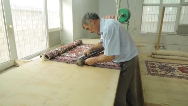 Ein Mann schneidet mit einer Spezialmaschine einen Teppich. Herstellung von handgefertigten Teppichen — Stockvideo