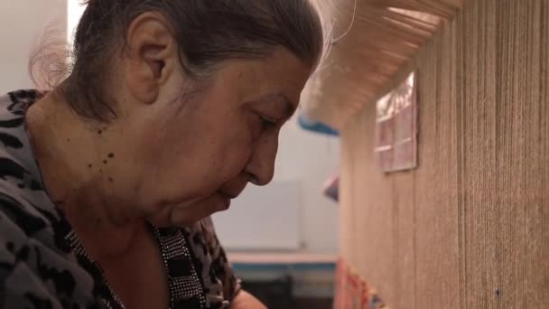 Starší orientální žena tkaní východní ručně vyrobený koberec — Stock video
