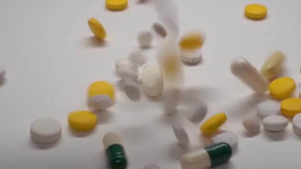 Huge number of different kinds pills falling on white background in slow motion. — Stock Video