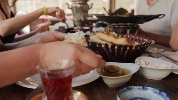 Люди снідають за столом у кафе, жінка кладе мед на шматочок піти — стокове відео