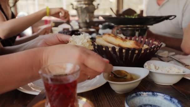 People have breakfast at a table in a cafe, woman puts honey on a piece of pita — 비디오