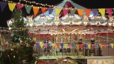 Yetişkinler ve çocuklar için bir tatil atlıkarıncası. Çok renkli ışıklar ve bayraklar.