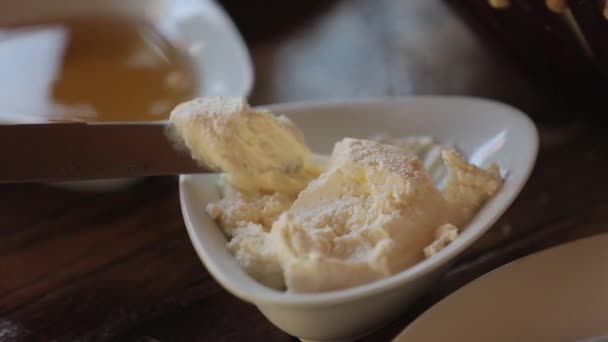 Fromage à pâte molle dans une petite tasse. Un homme frotte du fromage avec un couteau sur du pain pita . — Video