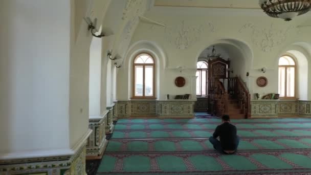 Un hombre solitario e inidentificable reza en la mezquita. Una pequeña mezquita vacía. Personas musulmanas — Vídeo de stock