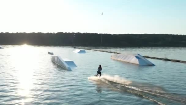 Chica wakeboarder montar el agua del lago. Toma aérea de un teleférico en un lago . — Vídeos de Stock