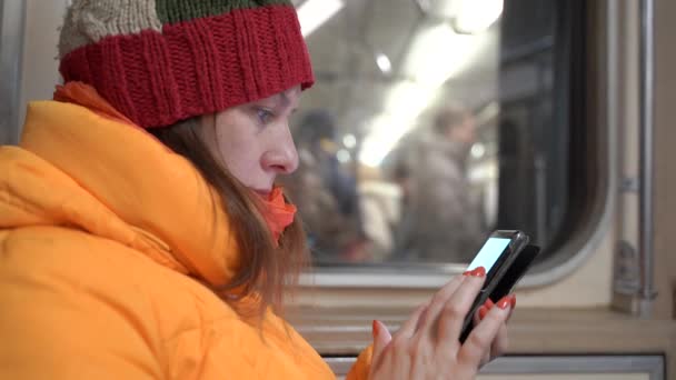 V metru sedí žena s mobilním telefonem. Něco čte. — Stock video