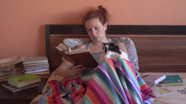 Woman at home on self-isolation. She reads a lot of books. — Stock Video