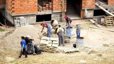  İşçiler (beton kum ve kaya yerleşim bölgesinde yeni bir ev inşası için kullanarak) çimento karıştırma.