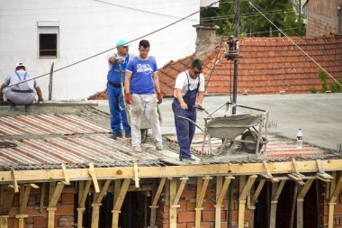  İnşaatçılar işçi kadar inşaat ekipman el arabası blok kullanarak kaldırma; yerleşim bölgesinde yeni bir ev inşa. İnşaat alanında. Gerçek işlemi.