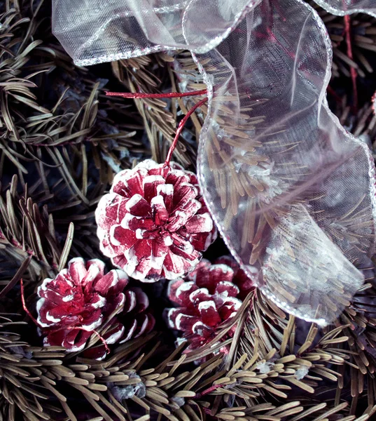 Winterhintergrund: schneebedeckte Tanne mit Tannenzapfen und weißem Zierrand. traditionelles Neujahrs- und Weihnachtsmotiv für Grußkarten in Burgundertönen. Künstlerische Retusche. — Stockfoto