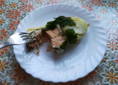 Ekşi krema ve yumurta soslu kızarmış kırmızı balık beyaz bir tabakta yatıyor..