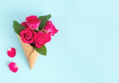 Mavi arka planda güzel güller olan gözleme külahı. Yaratıcı bahar çiçekleri. Kopya Boşluğu - Sevgililer Günü, 8 Mart, Anneler Günü ve Kadınlar Günü konsepti.