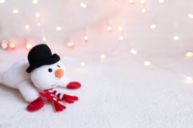 Soyut Noel ışıkları arka planında şık şapkalı ve eşarplı komik kardan adam. Tebrik kartı şablonu ve yeni yıl telif uzayı ile birlikte. Ros 'taki Bokeh Noel ışıklarının soyut dokusu